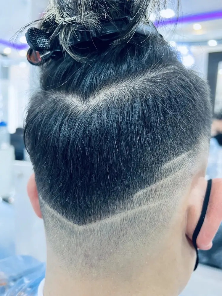 Fade with a V line design at the back, done at Groom Studio